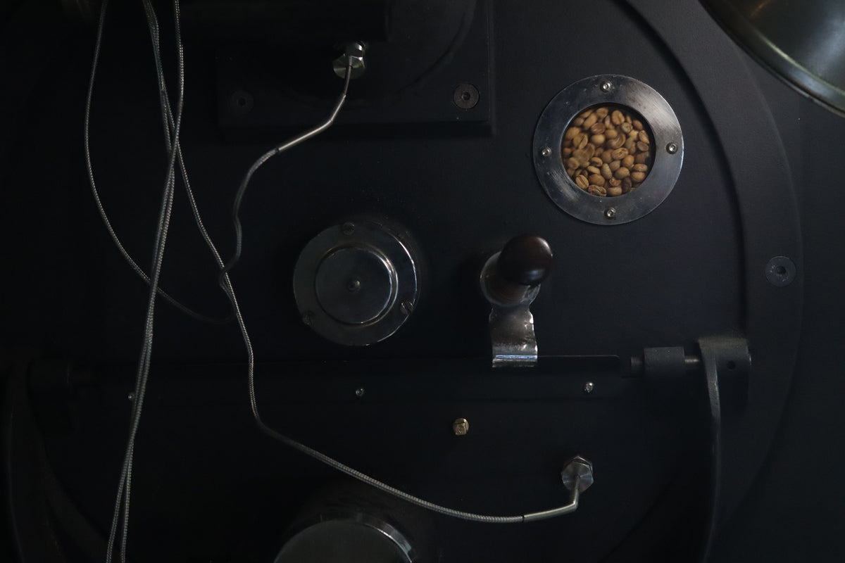 Coffee beans visible through the sight glass of the Squarebox Probat roaster.
